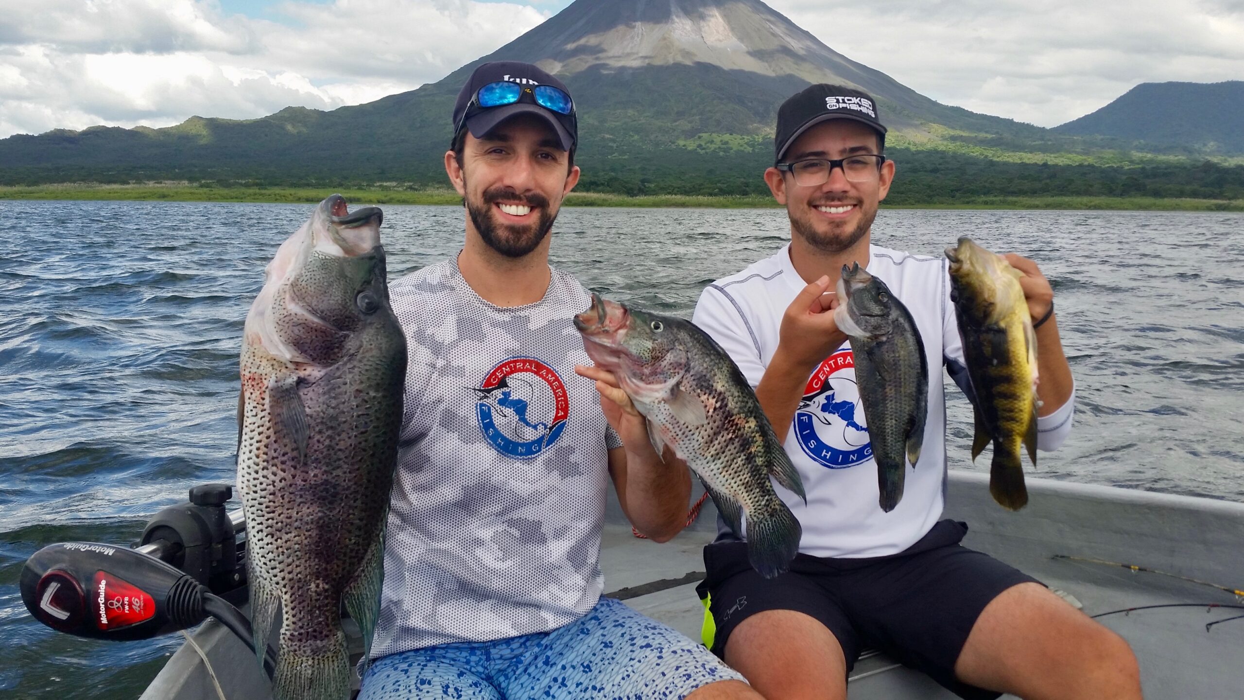 Central America Fishing owner Chris Atkins and friend with rainbow bass and jaguar bass in front of the Arenal Volcano